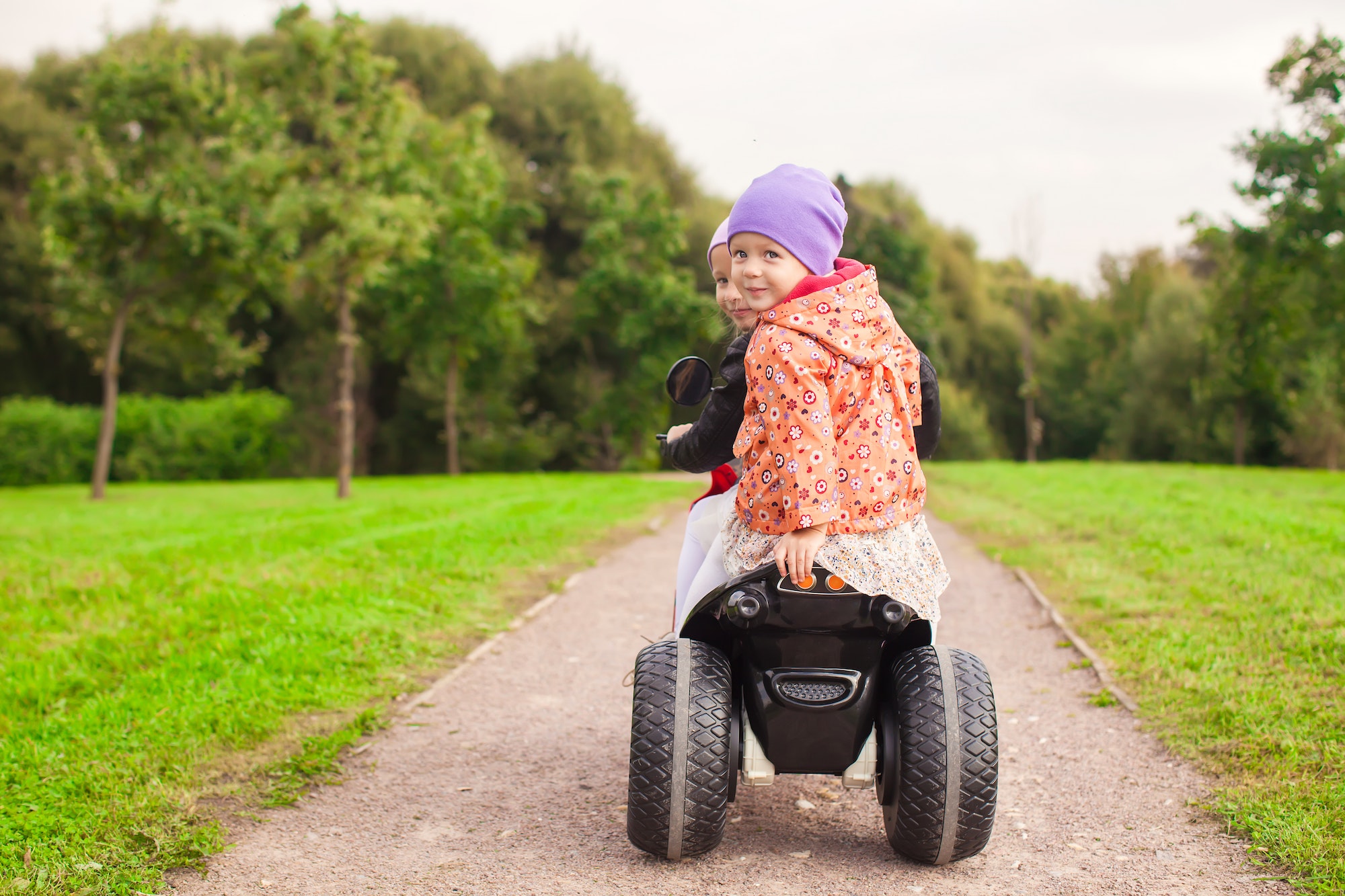 Happy little cute girls ride a motorbike outside